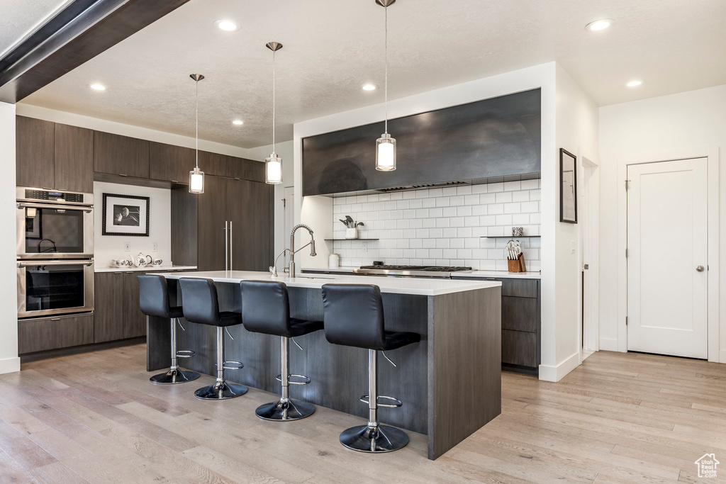 Kitchen featuring modern cabinets, appliances with stainless steel finishes, a breakfast bar area, and recessed lighting