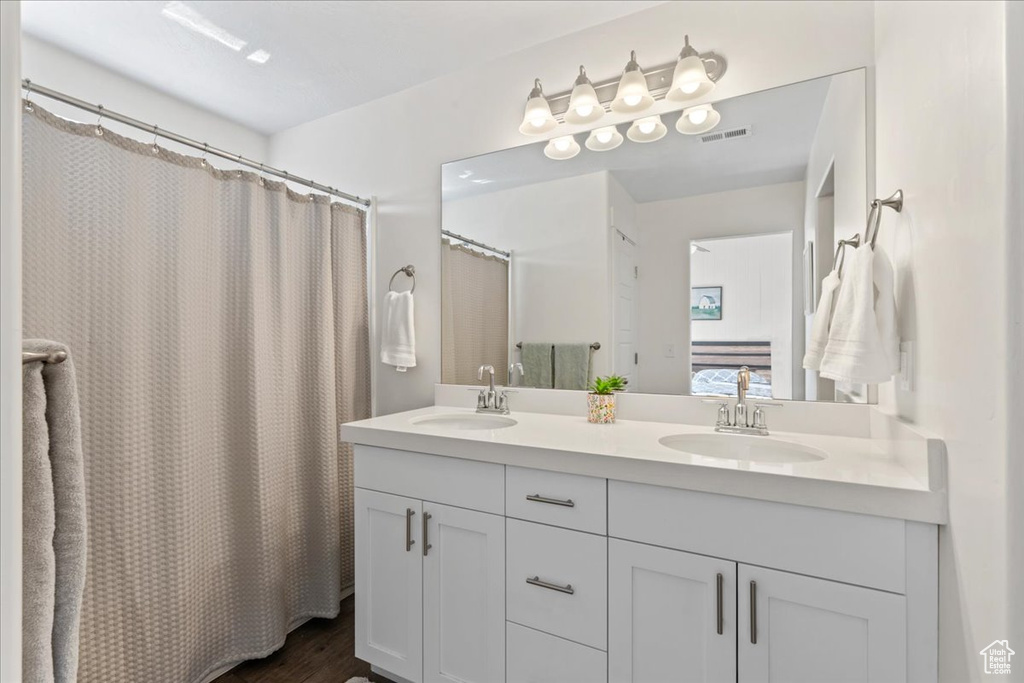 Bathroom with double vanity, wood finished floors, and a shower with shower curtain