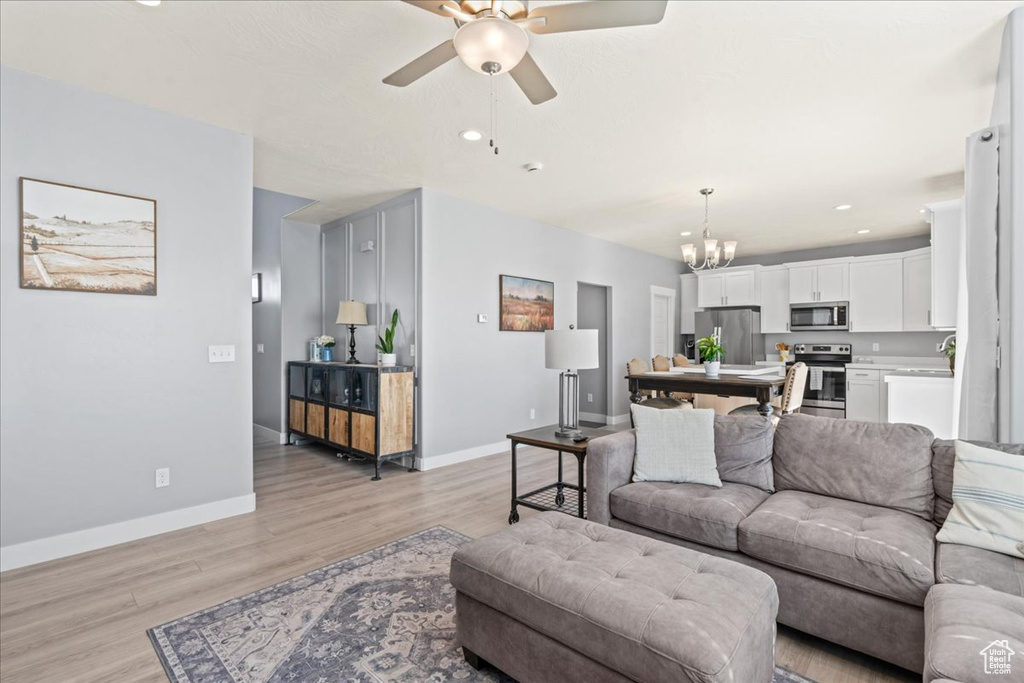 Living area featuring ceiling fan, a chandelier, light wood-style flooring, baseboards, and recessed lighting