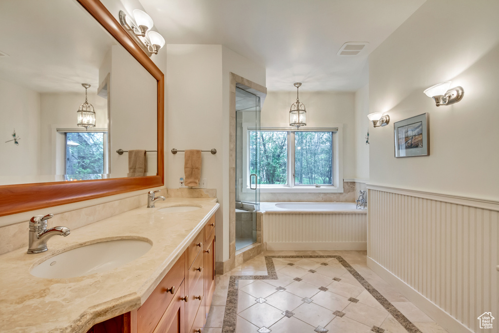 Full bath featuring healthy amount of natural light, a garden tub, double vanity, a stall shower, and wainscoting