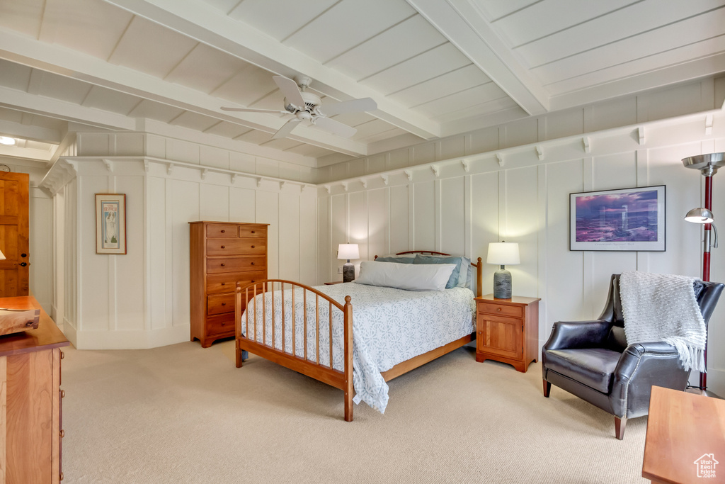 Bedroom with a decorative wall, light carpet, beam ceiling, and ceiling fan