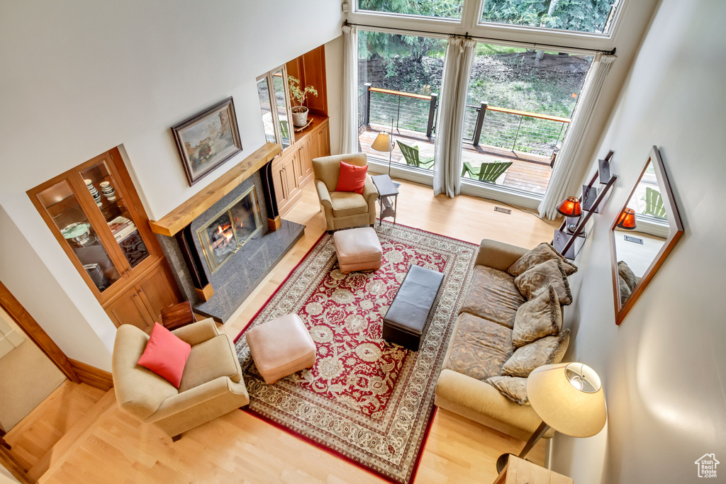 Living room with wood finished floors, a high end fireplace, and a towering ceiling