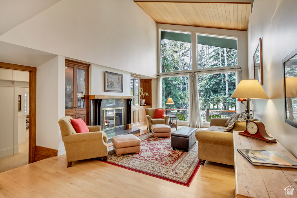 Living area featuring a towering ceiling, a fireplace, wood finished floors, and wooden ceiling