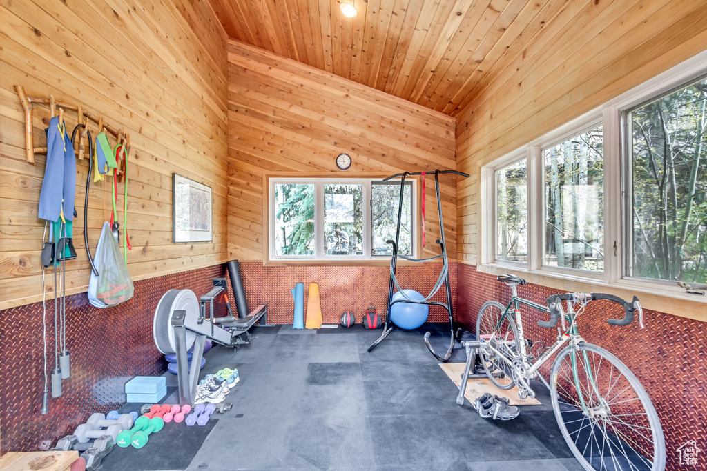 Exercise room featuring plenty of natural light, wooden walls, and wooden ceiling