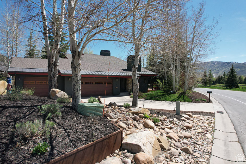 View of front of property with a garage, a chimney, a mountain view, a standing seam roof, and roof with shingles