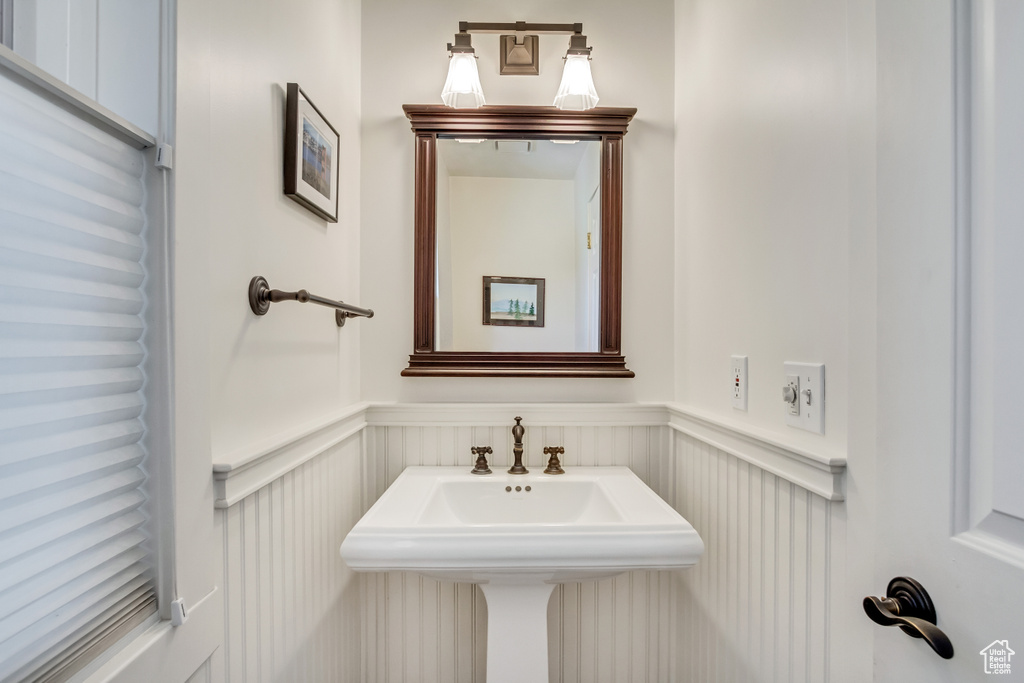 Bathroom featuring a wainscoted wall, a decorative wall, and a sink