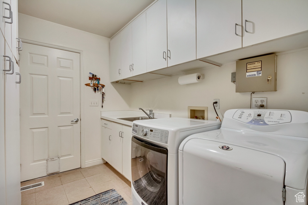 Washroom with washing machine and dryer, cabinet space, and light tile patterned flooring