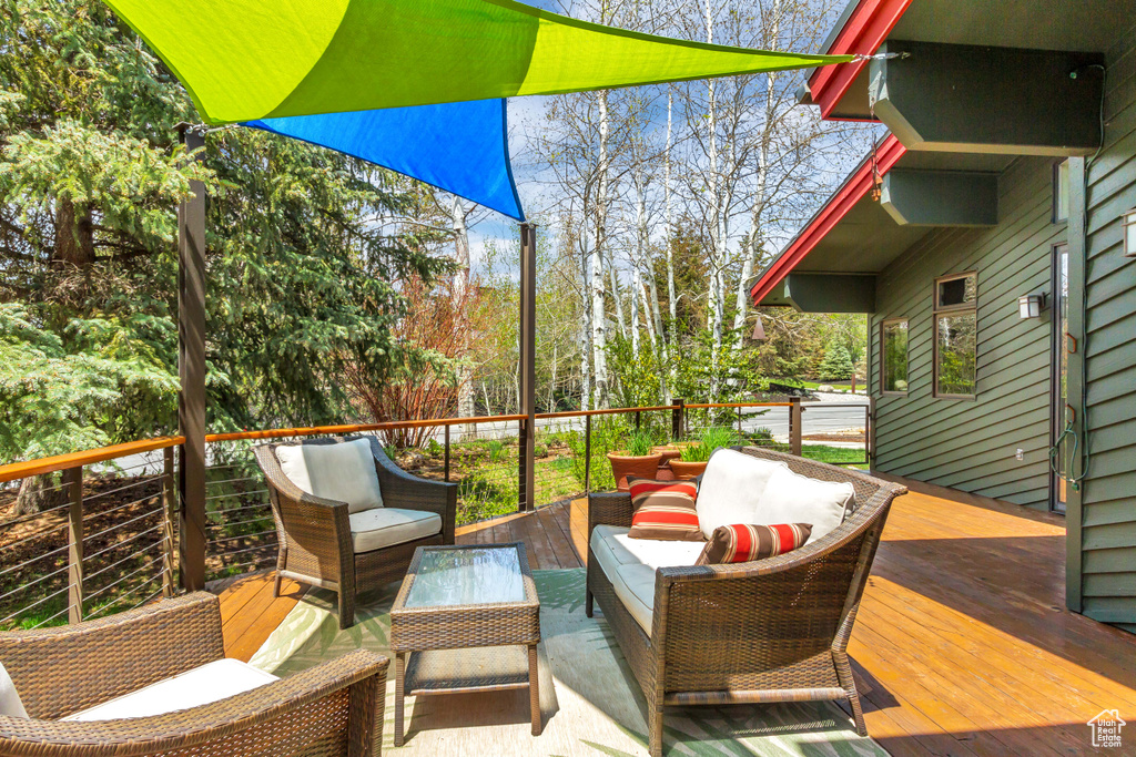 Wooden deck featuring an outdoor hangout area and view of wooded area