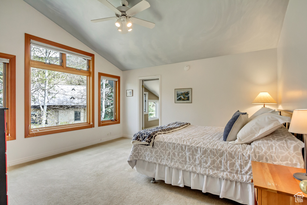 Bedroom with light colored carpet, lofted ceiling, multiple windows, baseboards, and a ceiling fan
