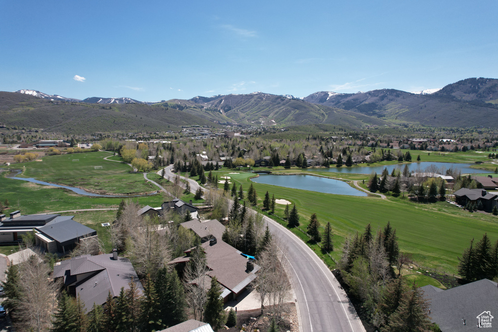 Aerial view of property and surrounding area featuring a water and mountain view, a local golf course, and nearby suburban area