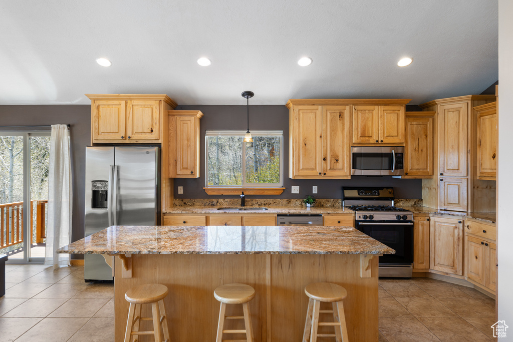 Kitchen with appliances with stainless steel finishes, a sink, light tile patterned flooring, recessed lighting, and a kitchen breakfast bar