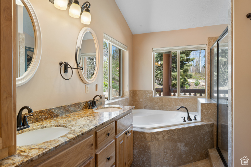 Bathroom with lofted ceiling, a bath, and double vanity