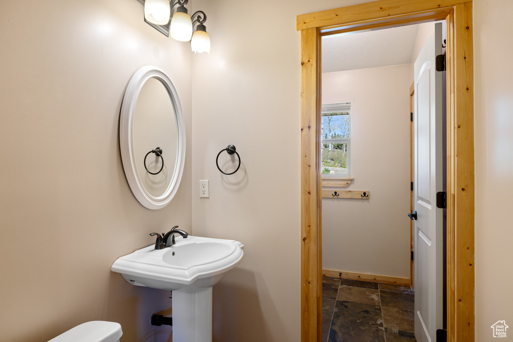Bathroom featuring stone tile floors, baseboards, and toilet