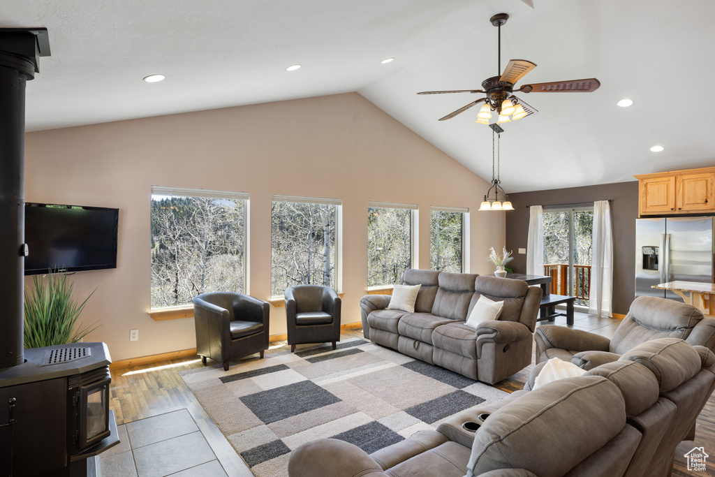 Living area with a wood stove, recessed lighting, a ceiling fan, high vaulted ceiling, and baseboards