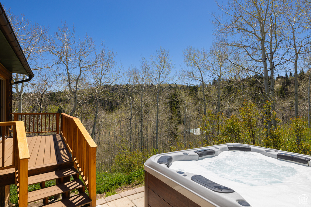 Deck featuring a wooded view and a hot tub