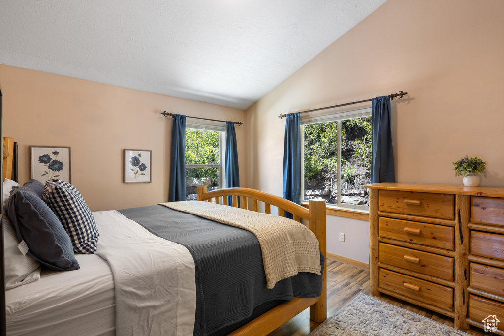 Bedroom with lofted ceiling, wood finished floors, and baseboards