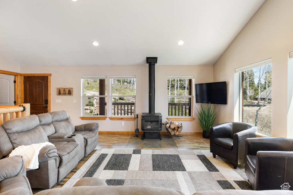 Living room featuring plenty of natural light, a wood stove, recessed lighting, light wood-type flooring, and vaulted ceiling