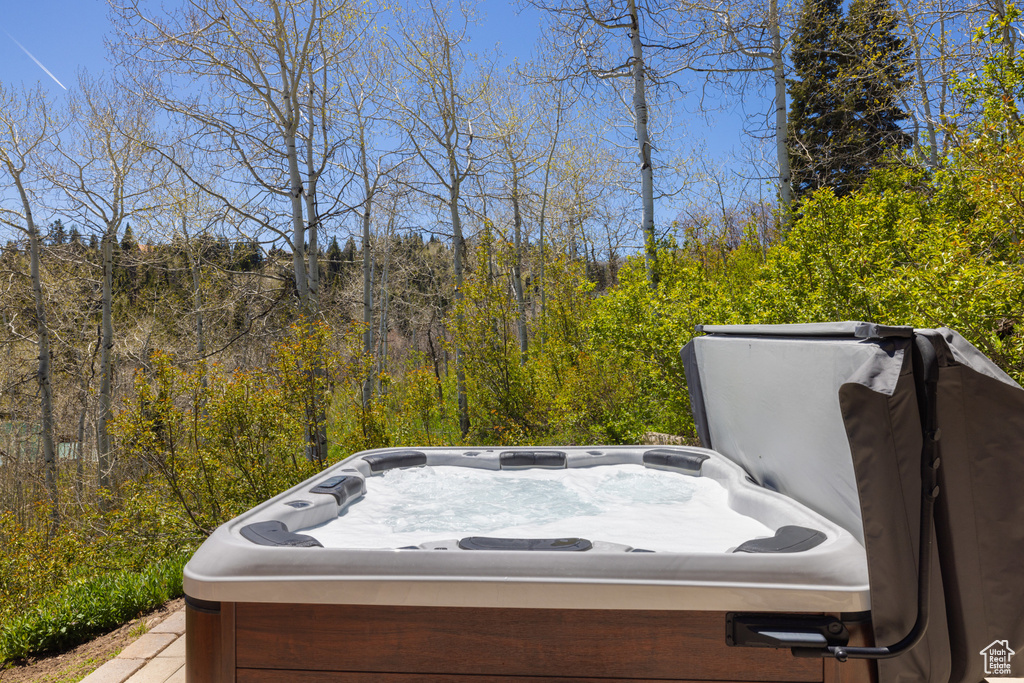 Deck with a hot tub and a wooded view