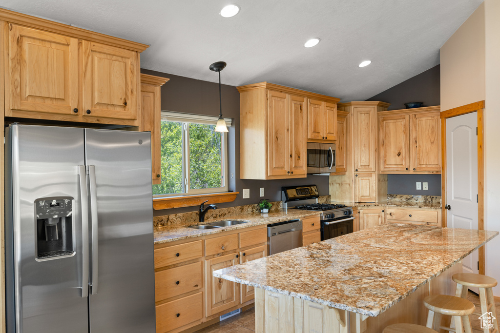 Kitchen with stainless steel appliances, a sink, a breakfast bar area, light stone countertops, and recessed lighting