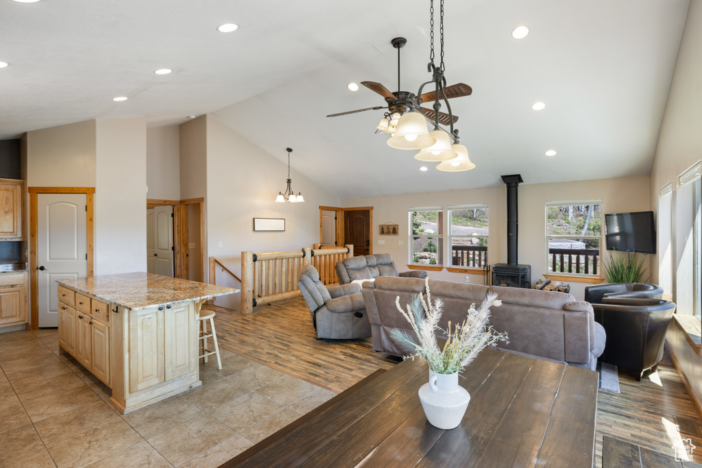 Dining space featuring a wood stove, a ceiling fan, high vaulted ceiling, recessed lighting, and light tile patterned floors