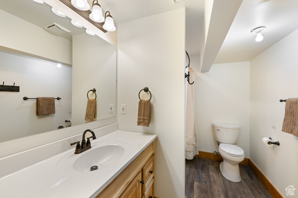 Full bathroom featuring wood finished floors, toilet, vanity, and baseboards