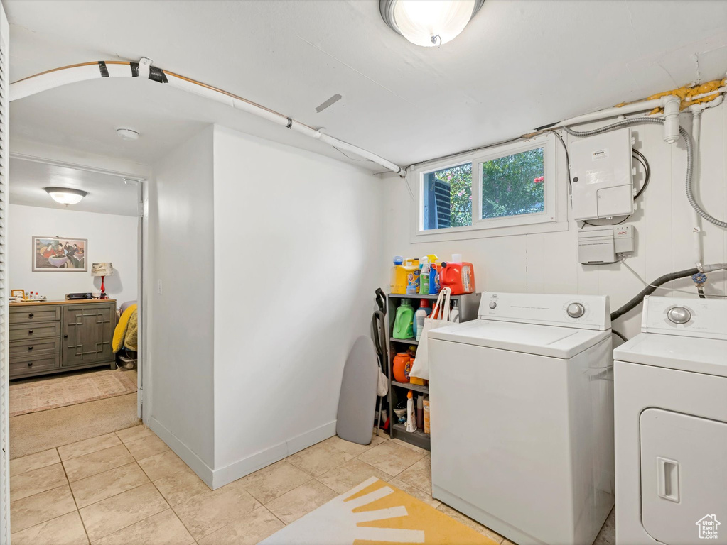 Laundry area with washing machine and dryer, light tile patterned floors, and baseboards
