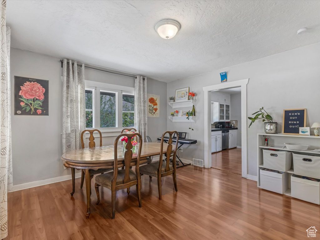 Dining area with wood finished floors, baseboards, and a textured ceiling
