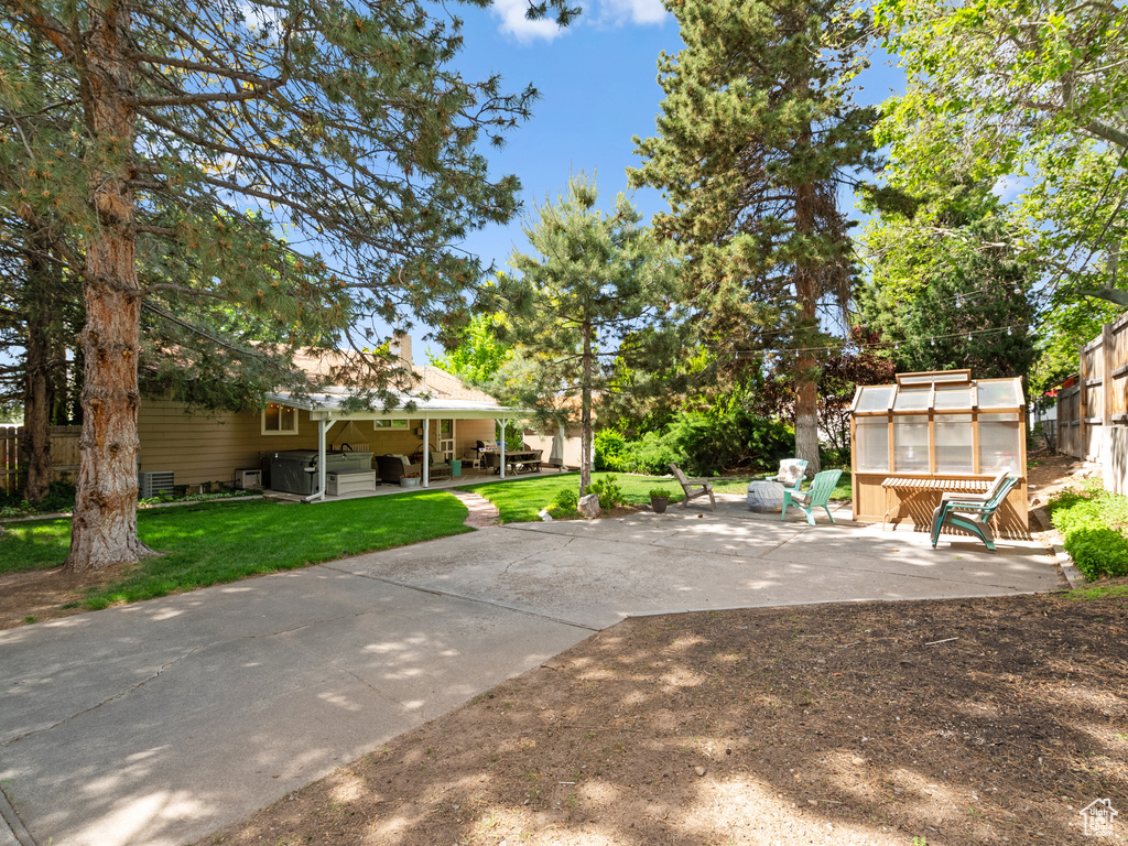View of yard with a jacuzzi, a greenhouse, a patio, and an outdoor structure