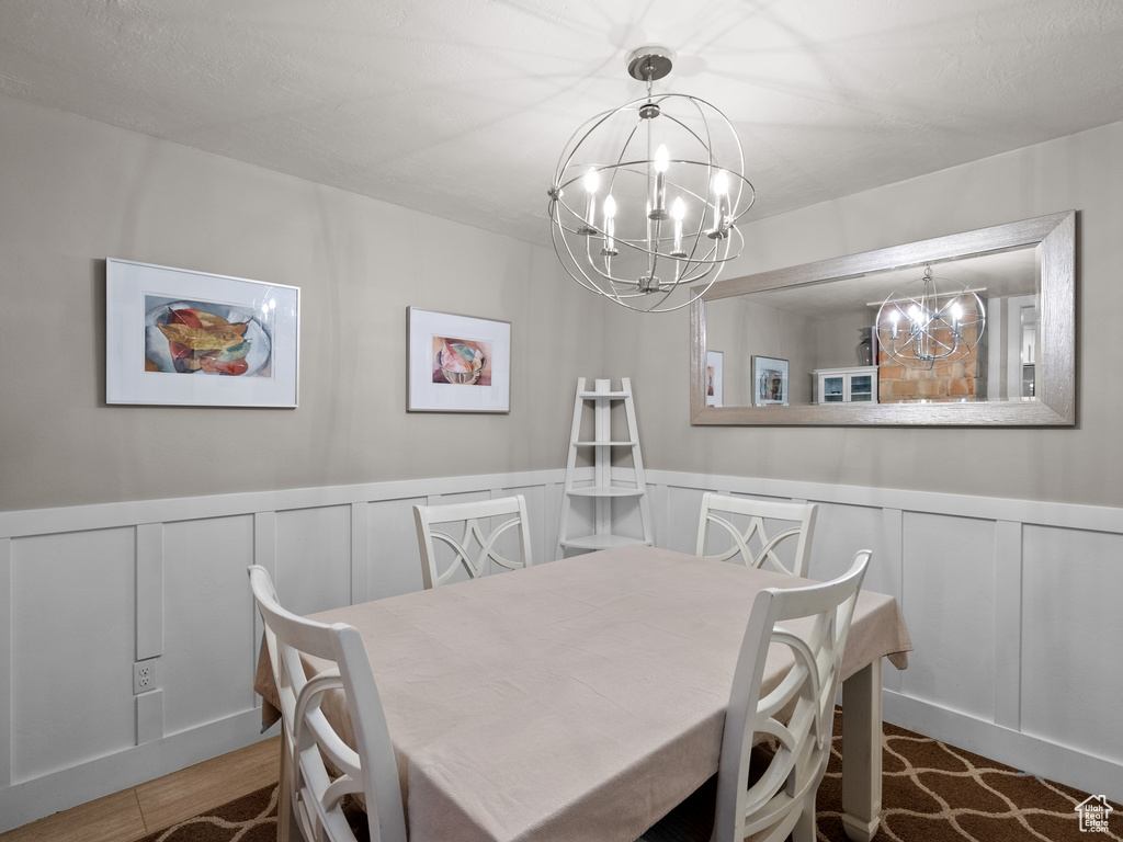 Dining room with a chandelier, a decorative wall, and wainscoting