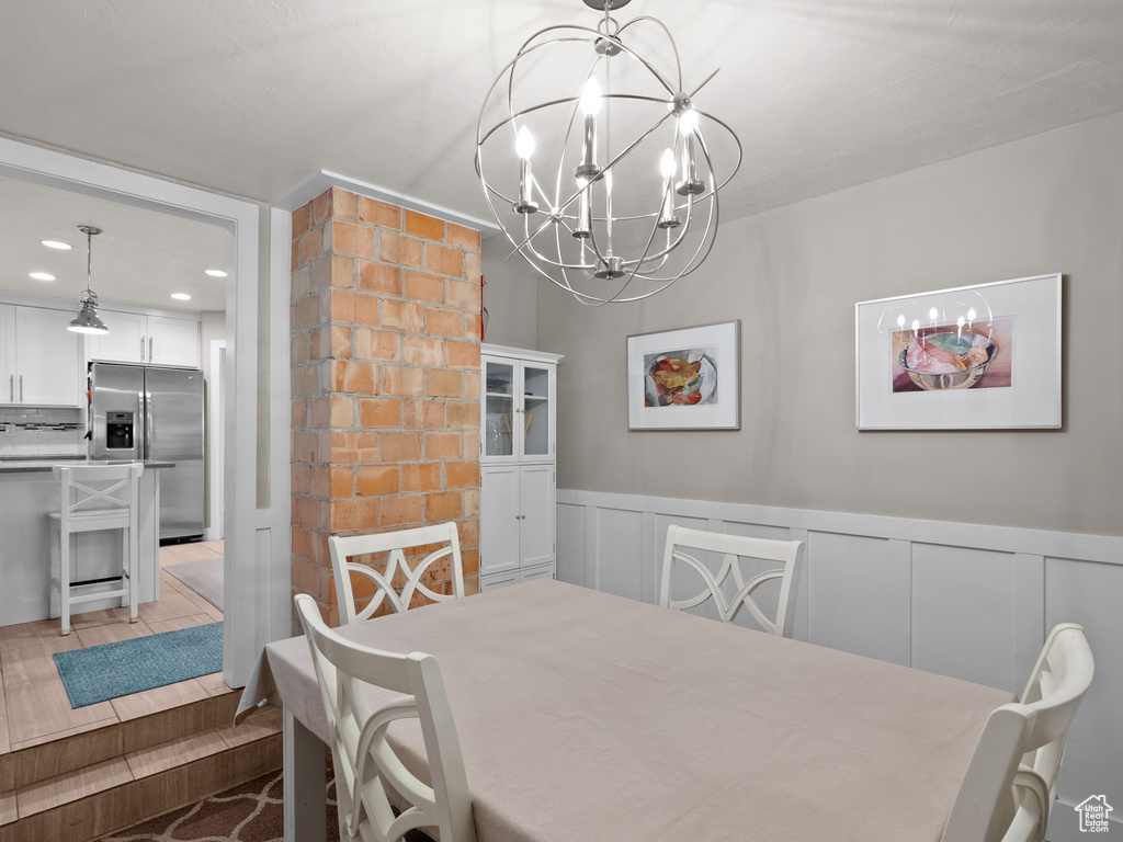 Dining room with a chandelier, a wainscoted wall, recessed lighting, and a decorative wall