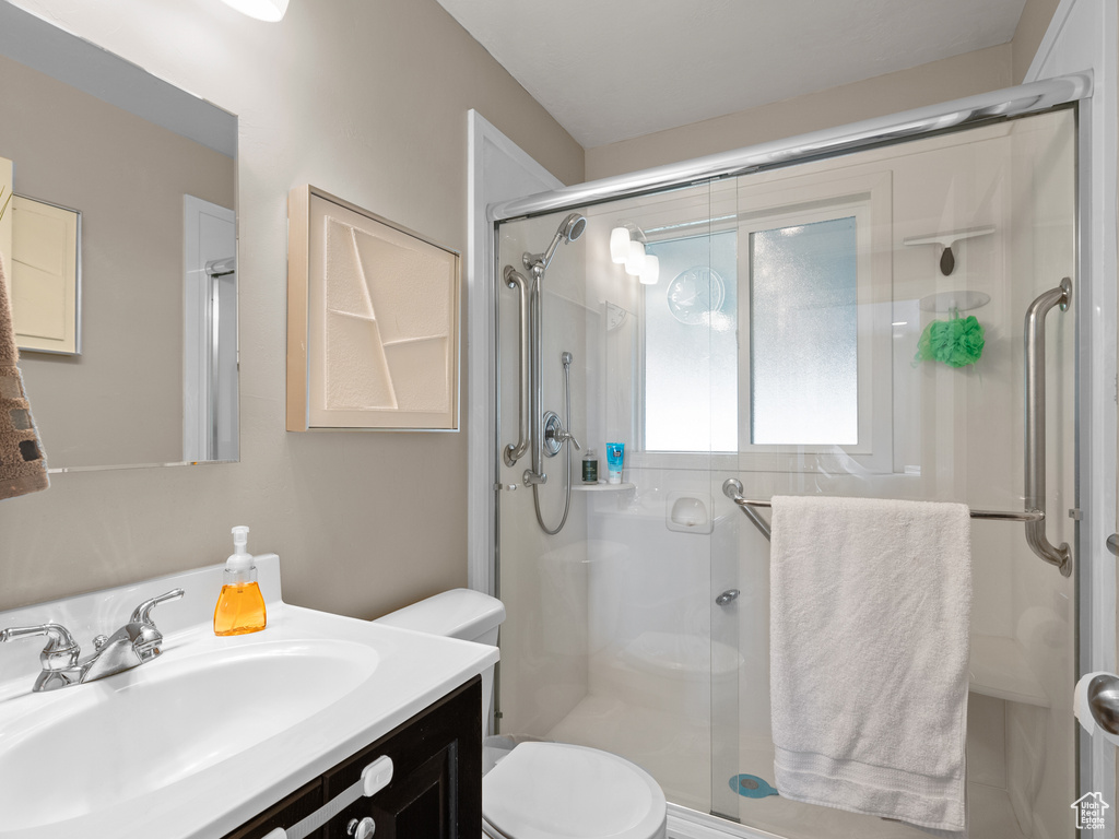 Bathroom featuring toilet, a shower stall, and vanity