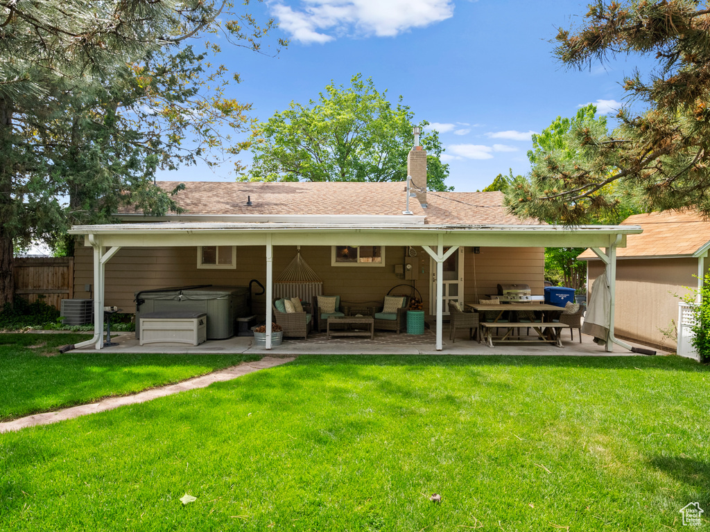 Rear view of property featuring a hot tub, a patio area, an outdoor hangout area, a chimney, and central AC unit