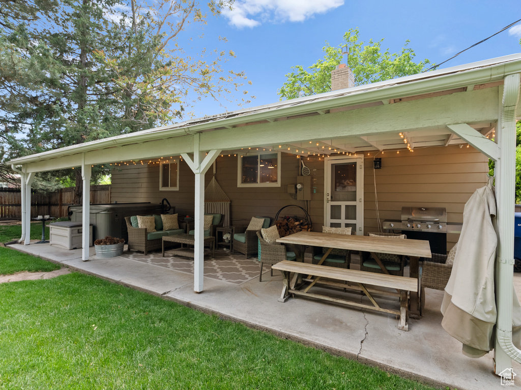 Rear view of property with a patio, a chimney, an outdoor living space, and a hot tub