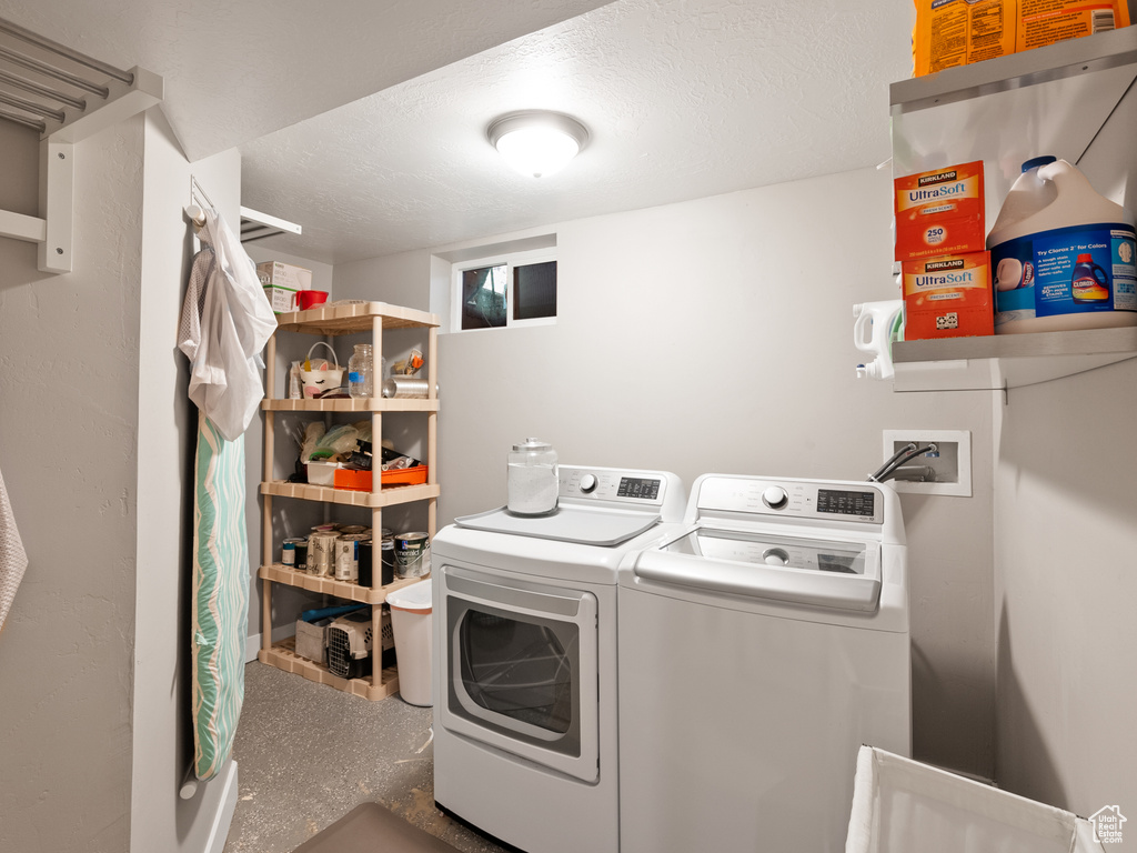 Washroom with washing machine and clothes dryer and a textured ceiling