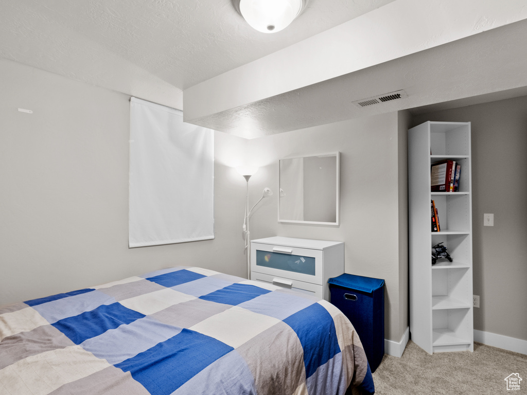 Bedroom with light carpet, baseboards, and a textured ceiling