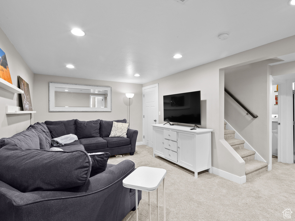 Living area with light colored carpet, recessed lighting, baseboards, and stairs