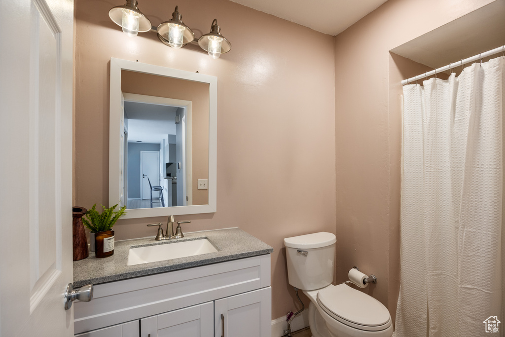 Full bath with toilet, vanity, and curtained shower