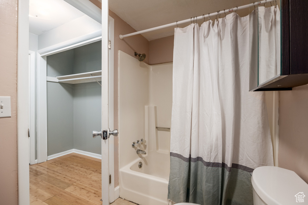 Full bathroom featuring shower / bath combination with curtain, toilet, wood finished floors, and baseboards