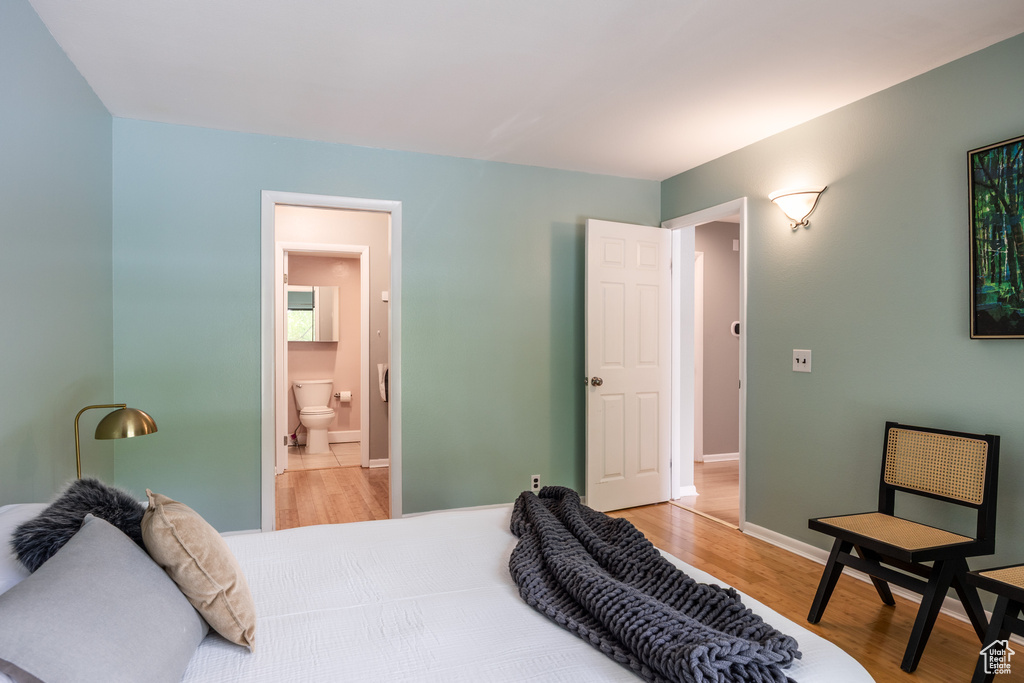 Bedroom with light wood-style flooring, baseboards, and connected bathroom