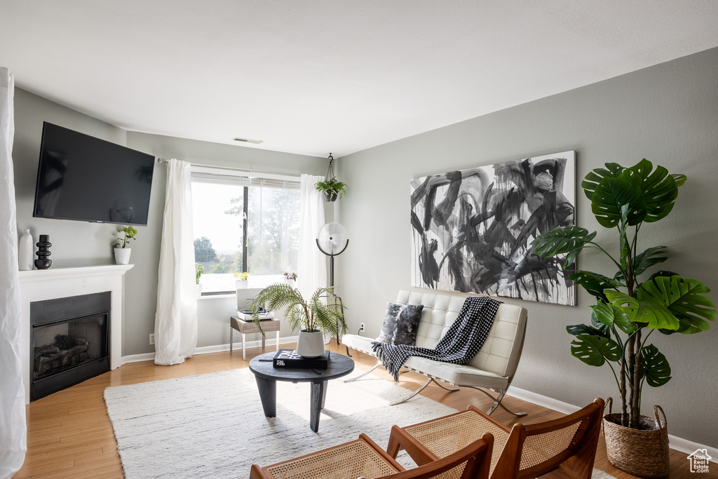 Living room featuring light wood finished floors, a glass covered fireplace, and baseboards
