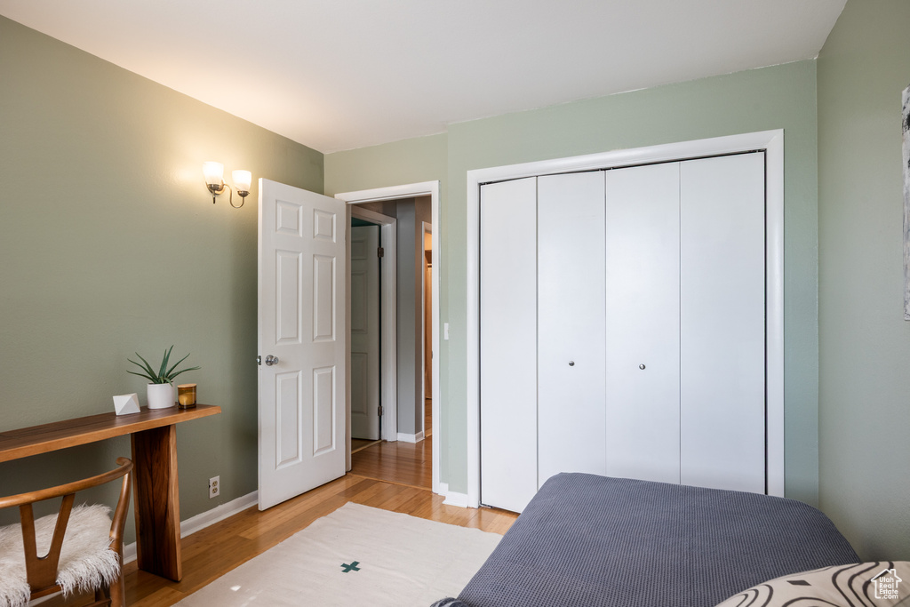 Bedroom with light wood-type flooring, a closet, and baseboards