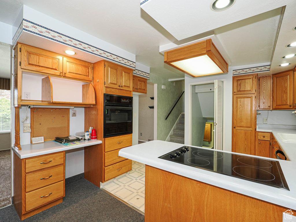 Kitchen featuring black appliances, light colored carpet, brown cabinets, light countertops, and recessed lighting