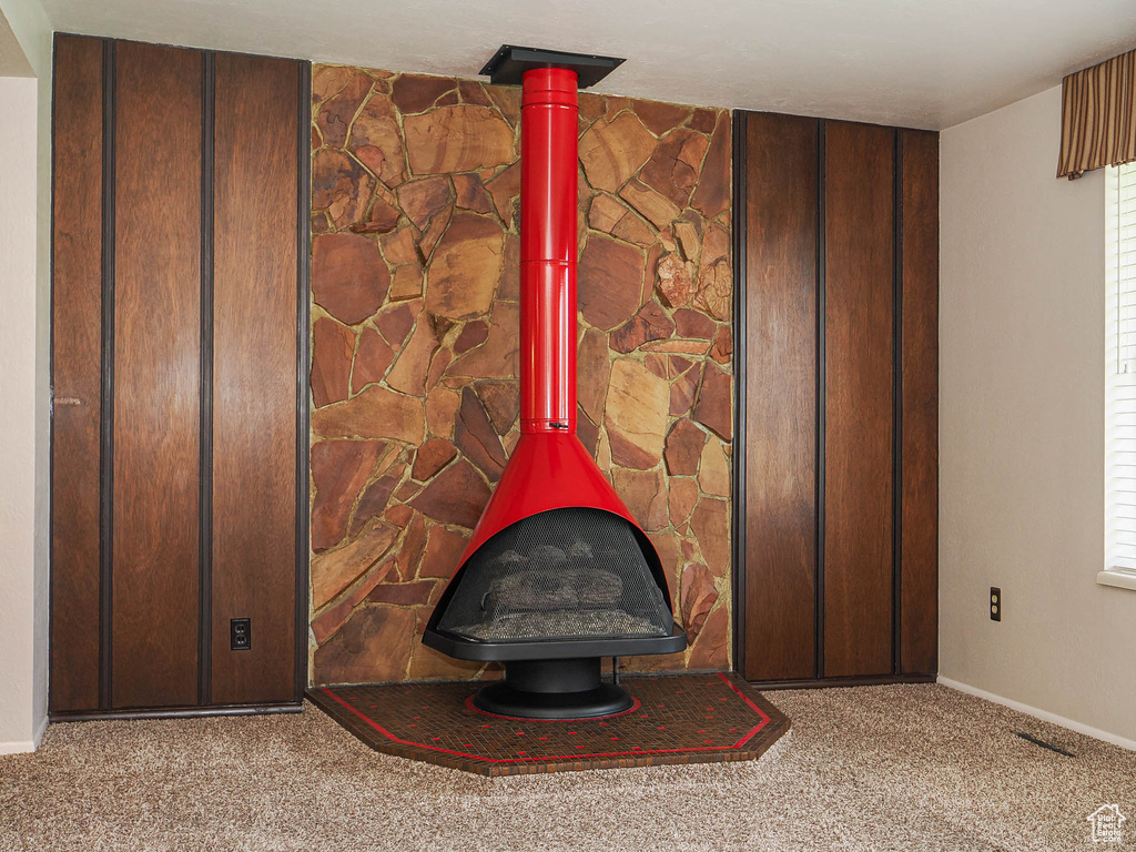 Detailed view of a wood stove, carpet floors, and baseboards