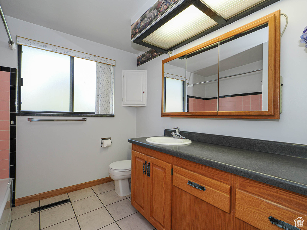 Full bathroom with plenty of natural light, vanity, toilet, and tile patterned flooring