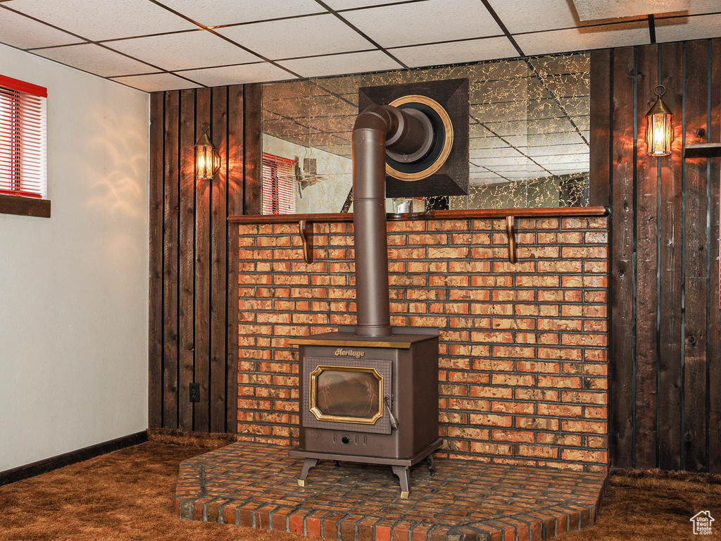Detailed view of carpet floors, a wood stove, a paneled ceiling, and baseboards