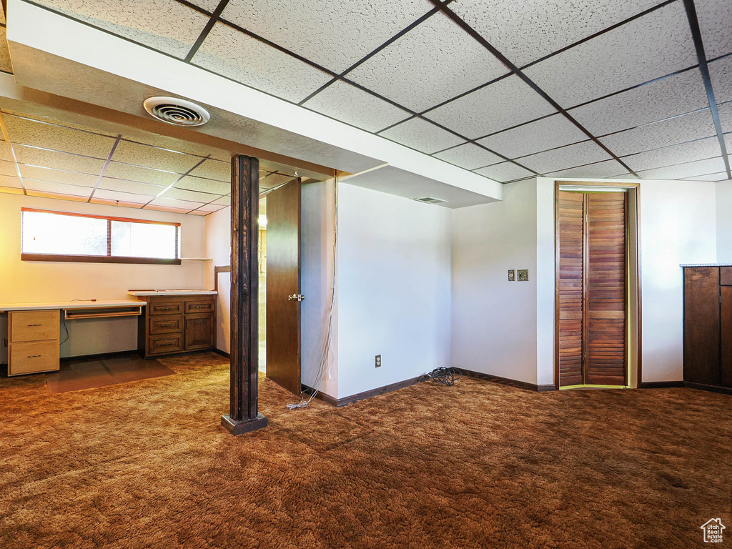 Below grade area with carpet floors, a paneled ceiling, and baseboards