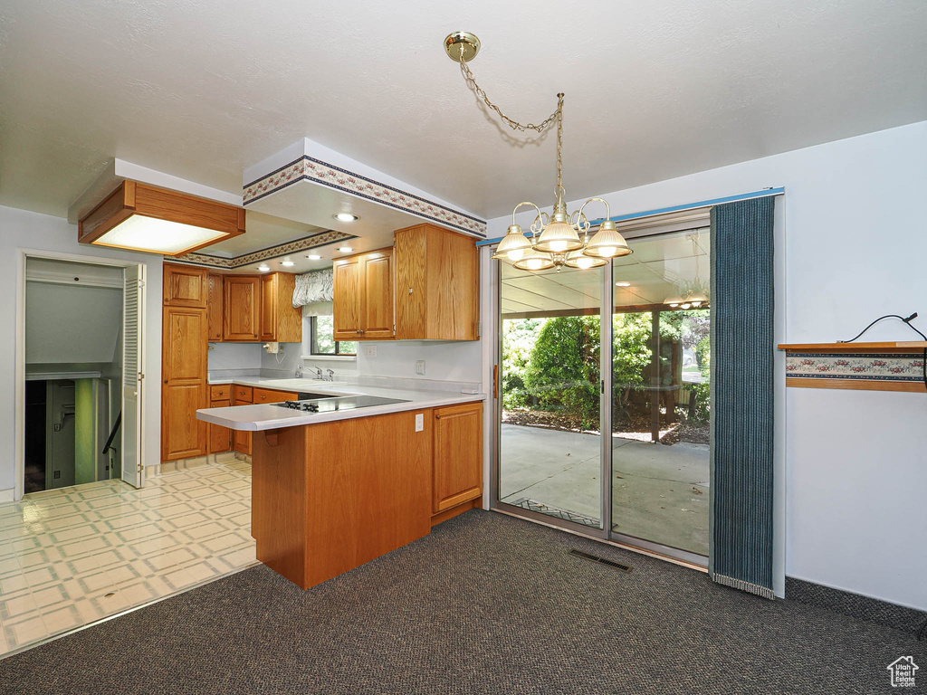 Kitchen with a peninsula, a chandelier, light countertops, a sink, and plenty of natural light