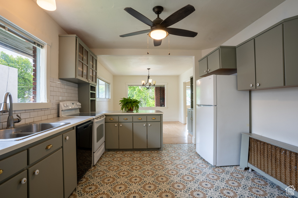 Kitchen featuring white appliances, gray cabinets, a sink, and a peninsula