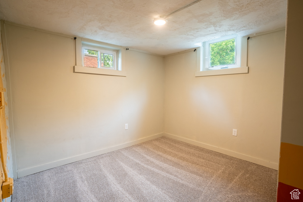 Basement featuring carpet, baseboards, and a textured ceiling