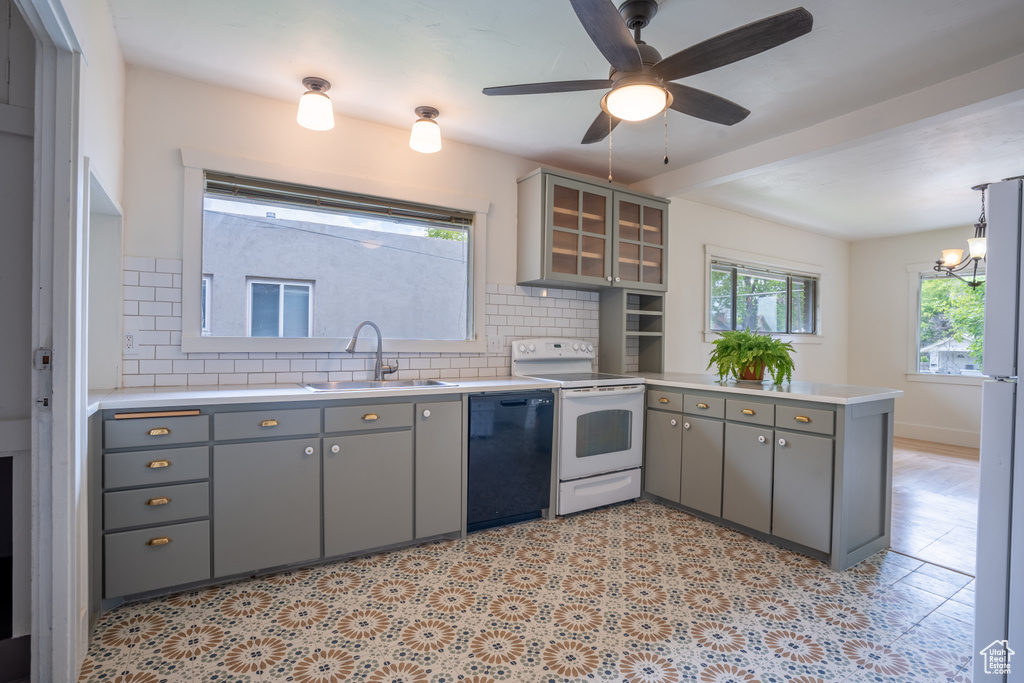 Kitchen with dishwasher, white range with electric cooktop, a sink, and gray cabinetry